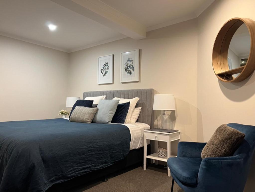 布赖特Westwood Lodge的一间卧室配有一张床、一把椅子和镜子