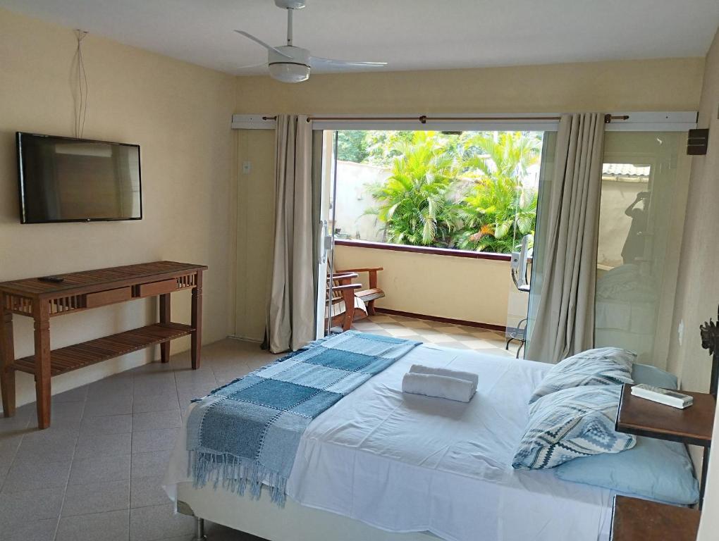 布希奥斯Andorinhas Suites的一间卧室配有一张床、一张书桌和一个窗户。