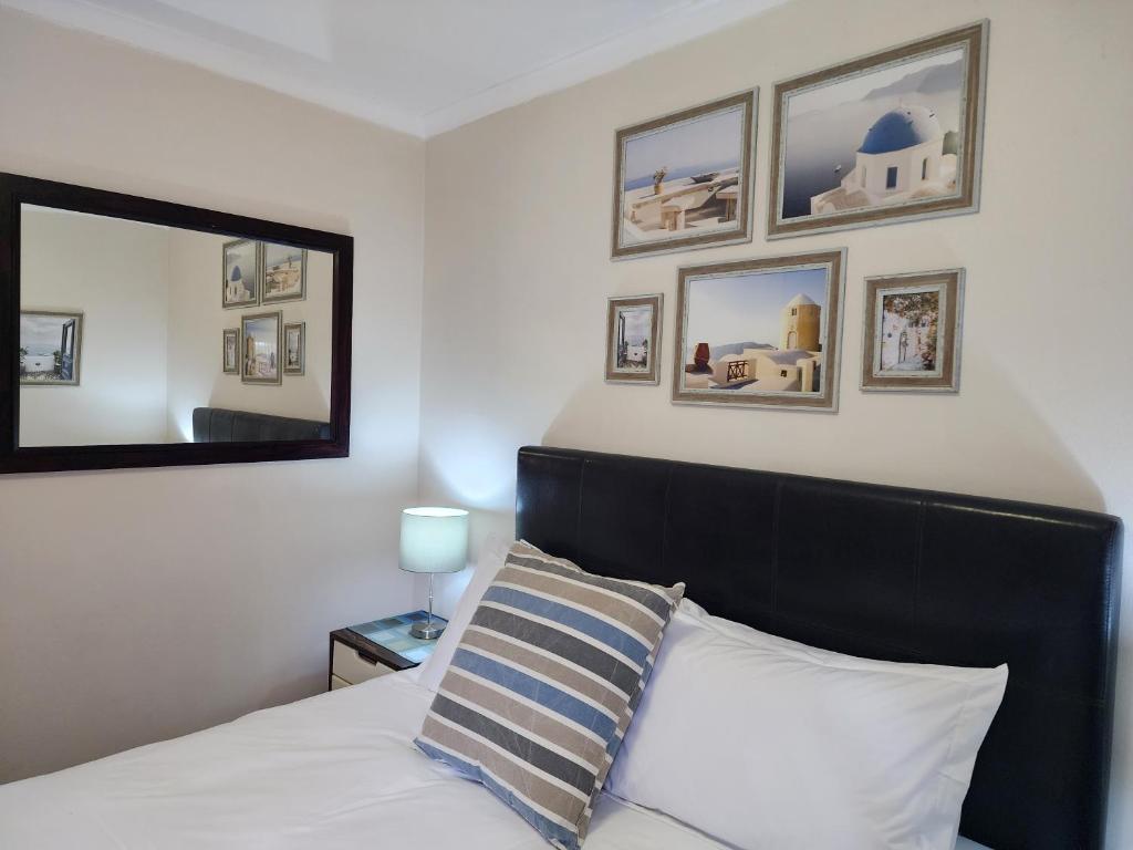 开普敦Little Greece的一间卧室配有一张带黑色床头板和镜子的床