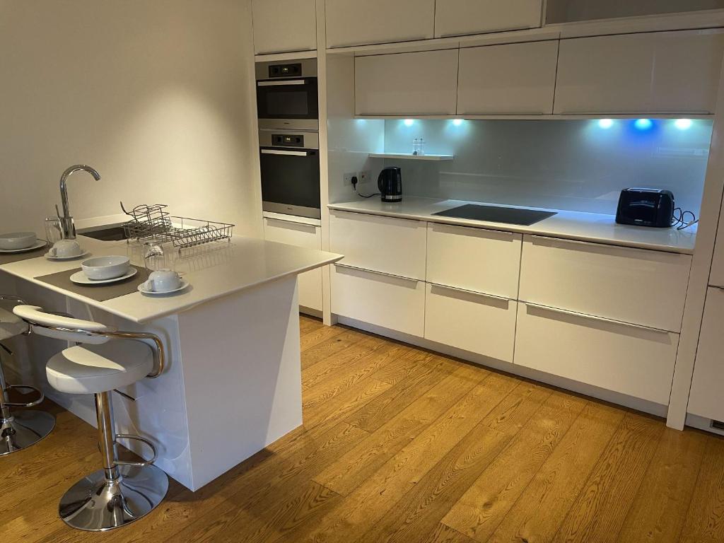 伦敦Clarges -Selfridges Luxury Apartment的厨房铺有木地板,配有白色橱柜。
