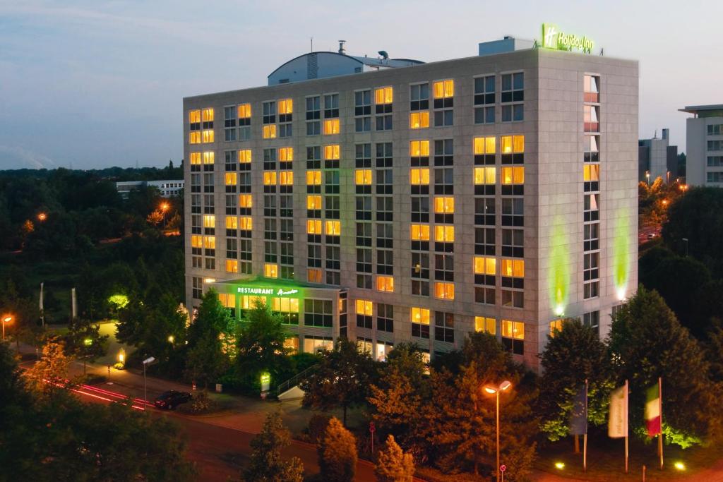 诺伊斯Holiday Inn Düsseldorf-Neuss, an IHG Hotel的一座高大的白色建筑,灯火通明