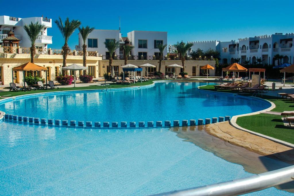 沙姆沙伊赫Palma Di Sharm Hollywood Resort的度假村内的大型游泳池,配有桌椅