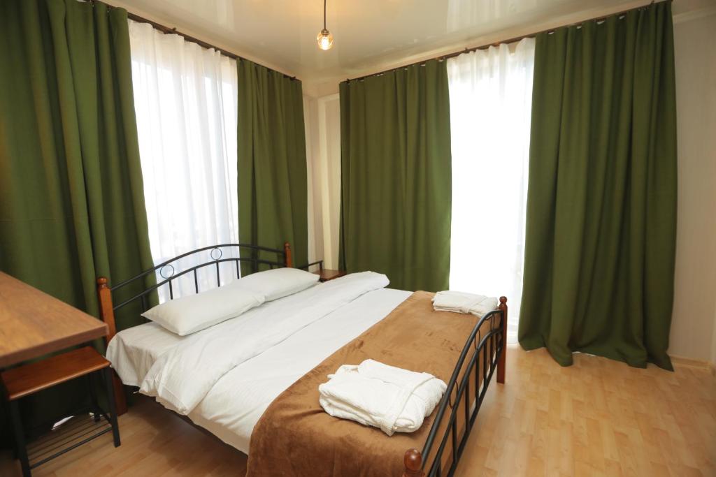 库塔伊西CHOGO的一间卧室配有一张带绿色窗帘的大床