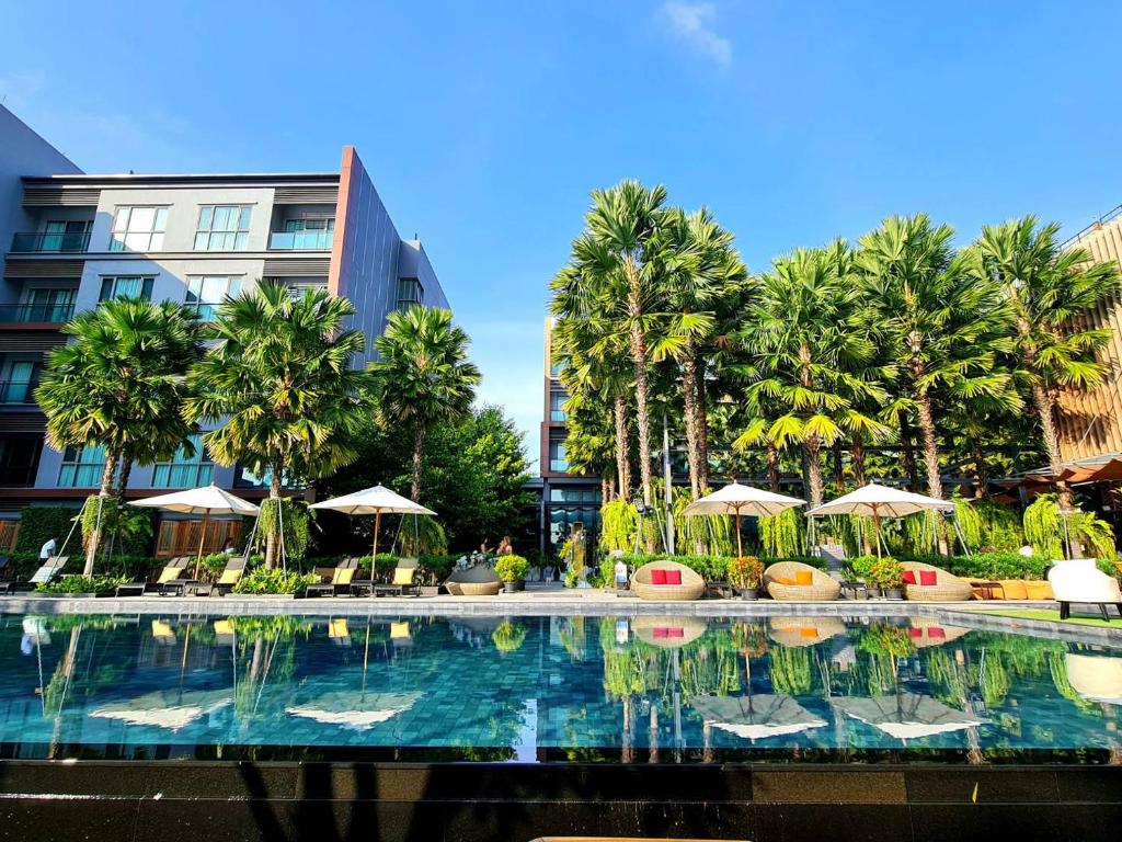 呵叻Aisana Hotel Korat的棕榈树建筑前的游泳池