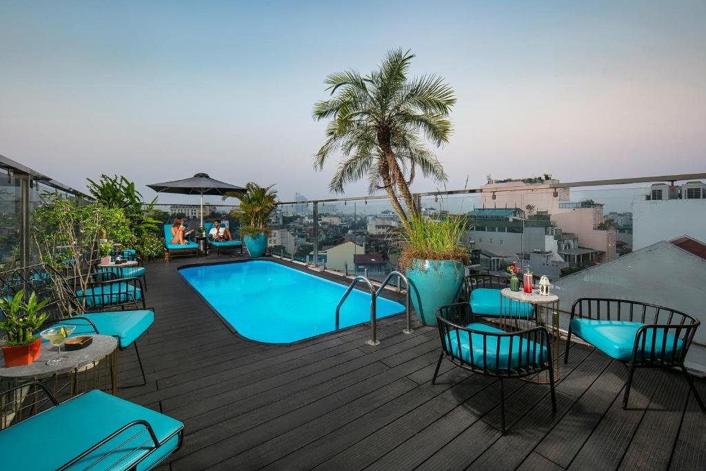 河内San Palace Hotel & Spa的屋顶甲板设有游泳池和桌椅