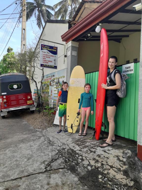 马特勒纪蕾海滩之家民宿的一名妇女和两名儿童站在冲浪板旁边