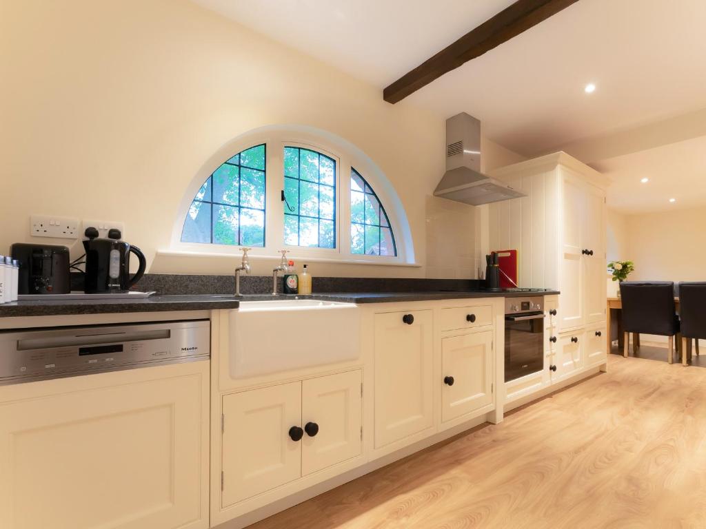 WisleyThe Turret的厨房配有白色橱柜、水槽和窗户。