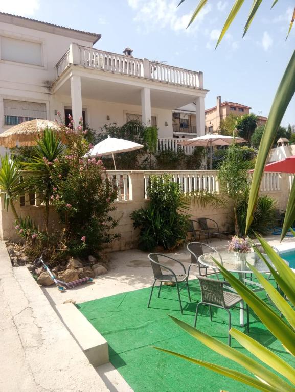 科尔多瓦Chalet Urbanización Alcolea的一座带椅子和绿色地毯的别墅,毗邻游泳池