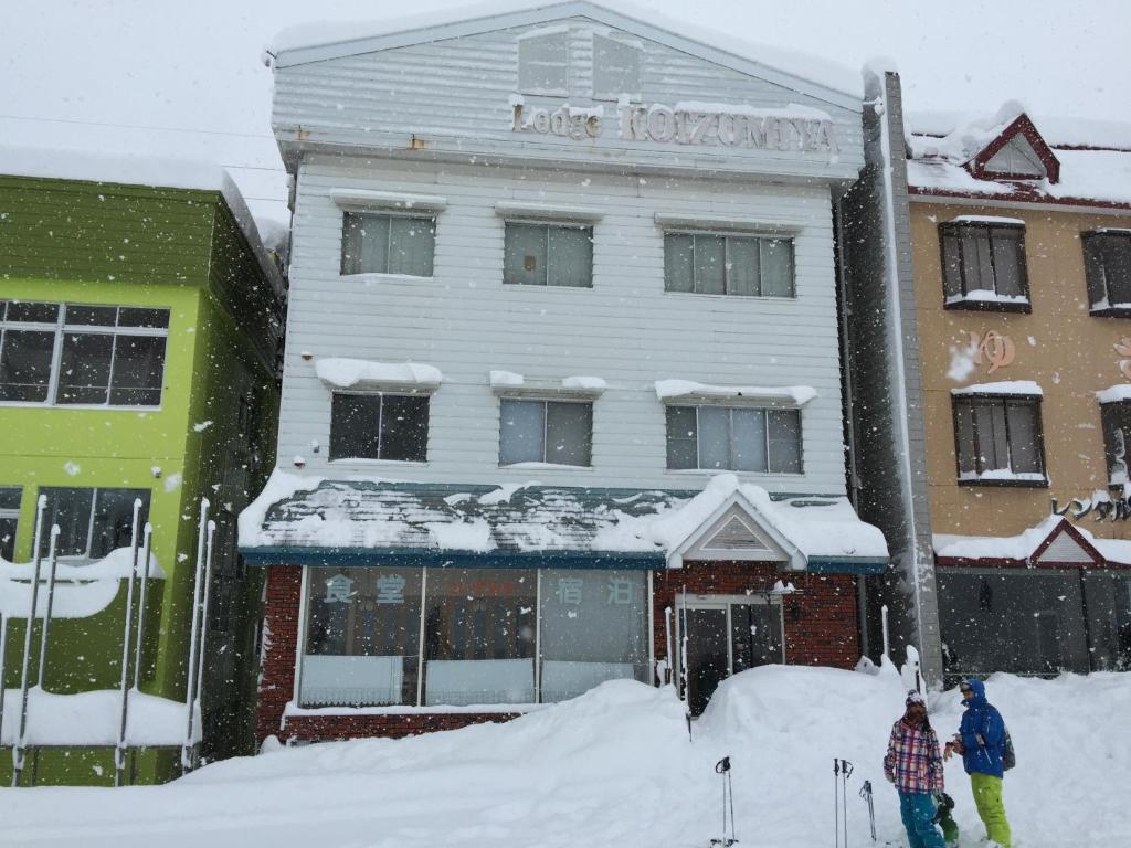 汤泽町Koizumiya - Vacation STAY 14238v的两个人站在一座建筑前面的雪地里