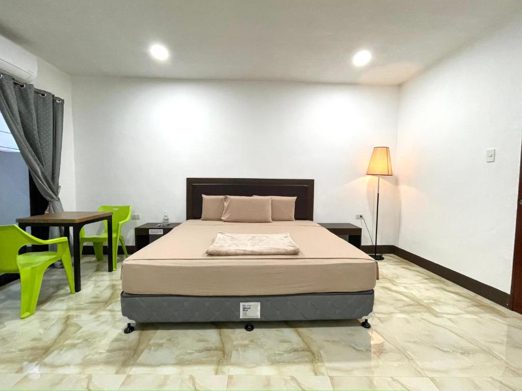 邦劳MGH Alona Resort的一间卧室配有一张床、一张桌子和绿色椅子