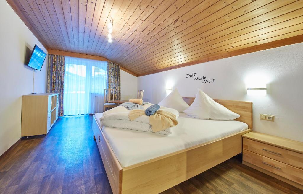 萨尔巴赫盖斯哈格酒店的一间卧室配有白色床单和木制天花板。