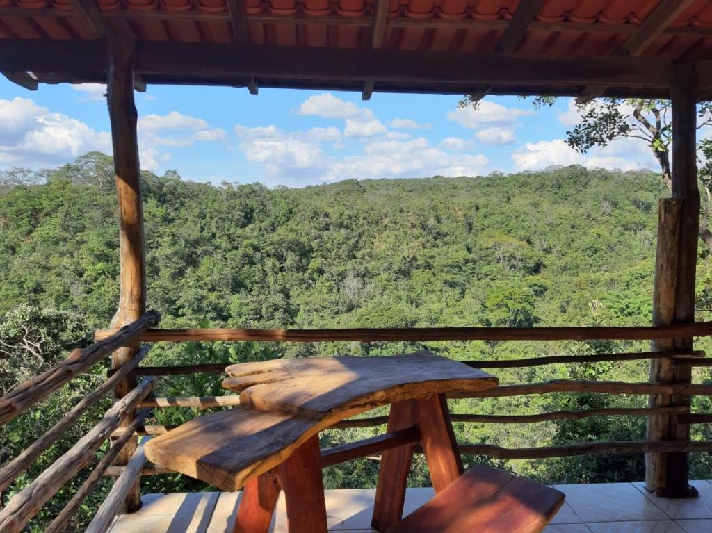 PlanaltinaFazenda Hotel Bem Ecológico的门廊上的木凳,享有森林美景