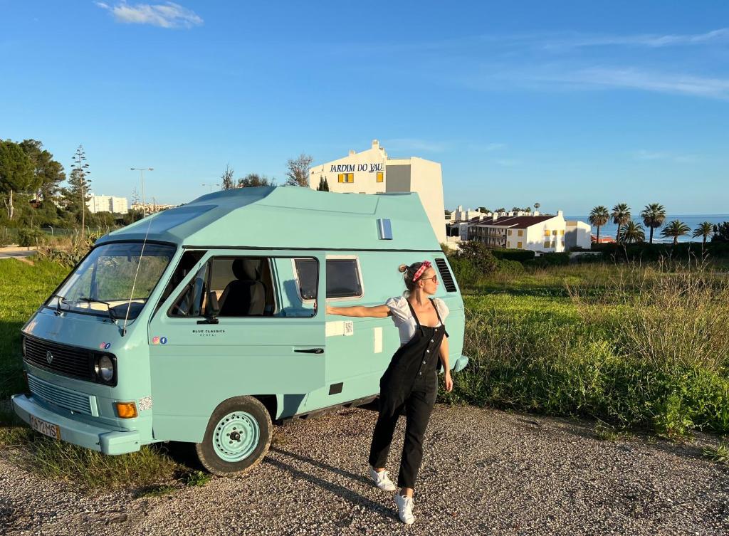 波尔蒂芒Rent a BlueClassics 's campervan vw T3 in Algarve au Portugal,的一位妇女站在一辆蓝色面包车旁边