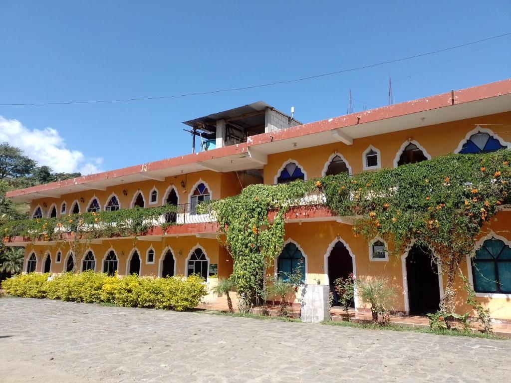 San Lucas TolimánHotel y Restaurante Tzutujil的一座橙色的建筑,旁边是常春藤
