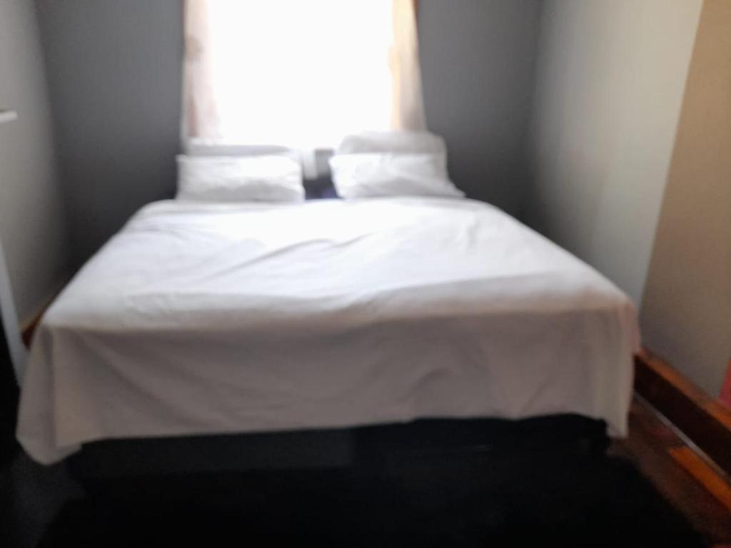 开普敦IKHAYA2 long street的一张带白色床单和窗户的床