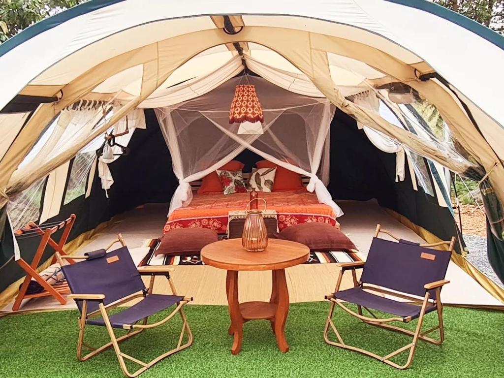 Ban Nong TakhainVilla Noina Glamping的帐篷配有1张床、2把椅子和1张桌子