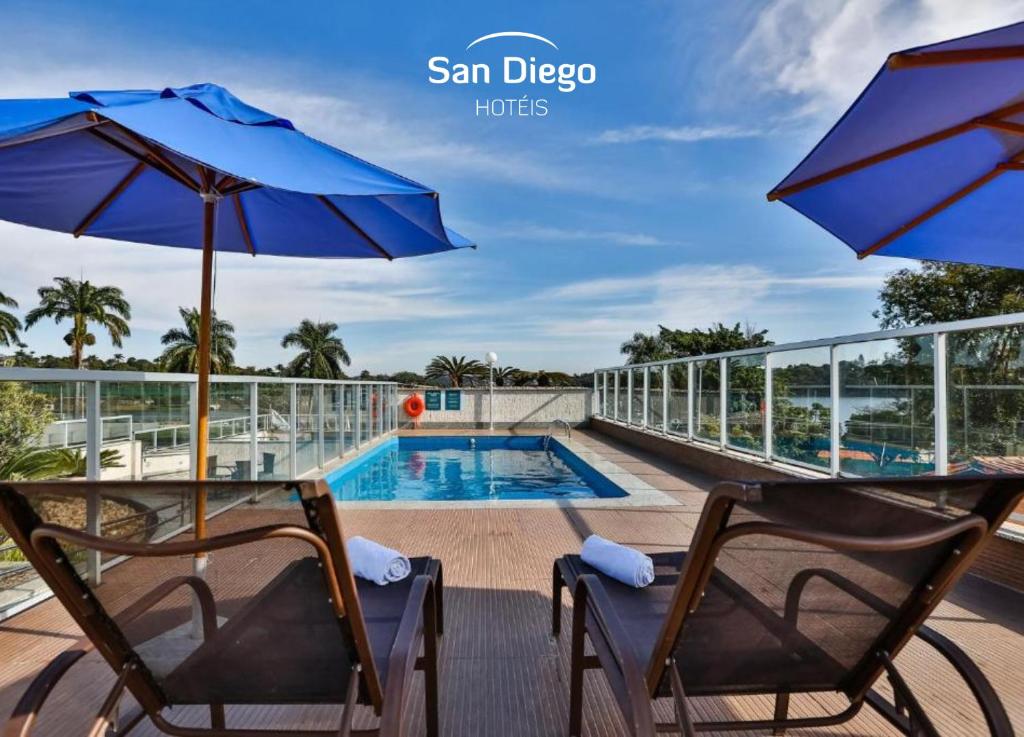 贝洛奥里藏特San Diego Suites Pampulha Hotel - Oficial的一个带两把椅子的阳台和一个游泳池