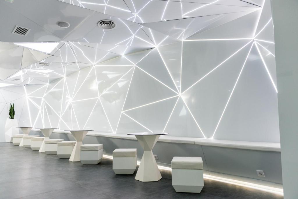 马德里Optimi Rooms Madrid的一间设有白色桌子和白色凳子的房间