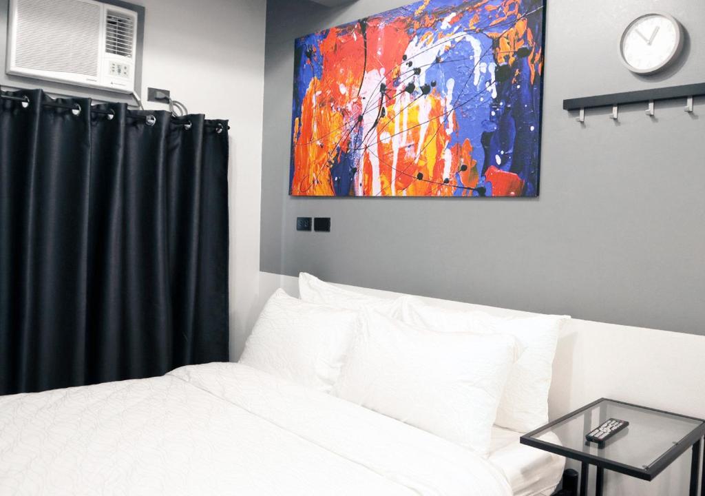 马尼拉mySTAY Hotel BGC West的卧室配有一张床,墙上挂有绘画作品