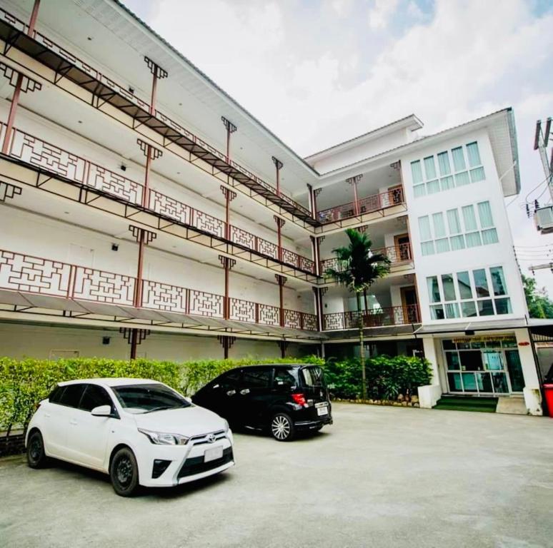 清迈INN Kham Apartment的两辆汽车停在大楼前的停车场