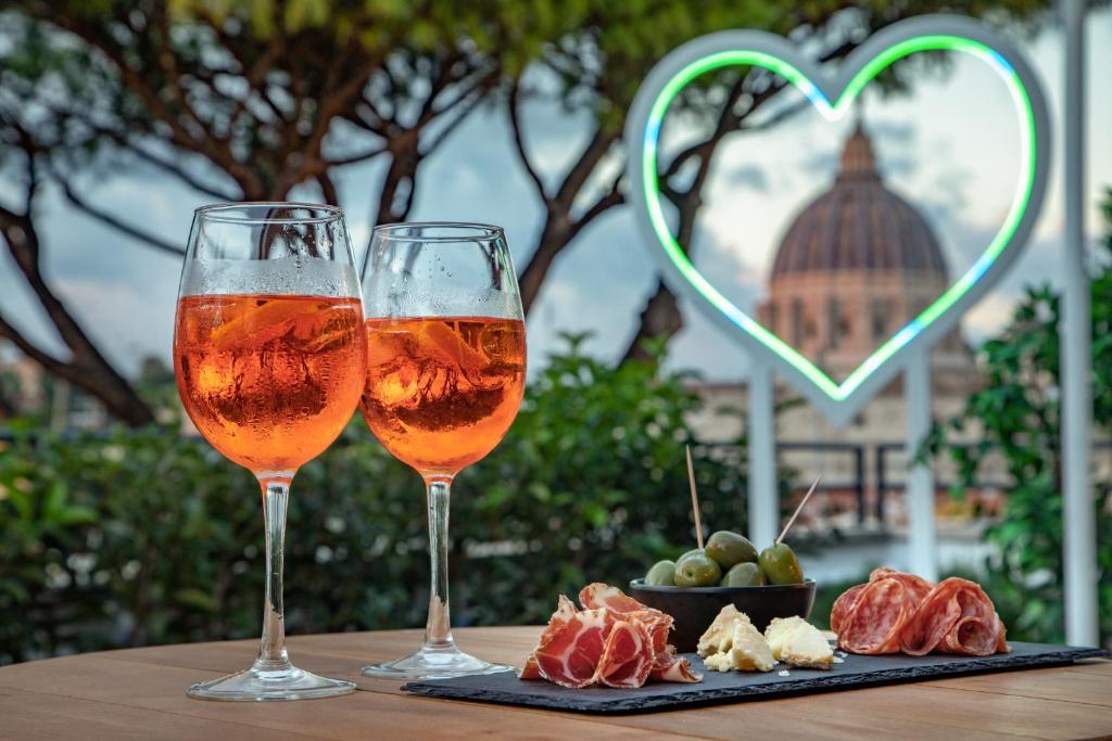 罗马Fragrance Hotel St. Peter的桌子上放着两杯葡萄酒和一盘水果