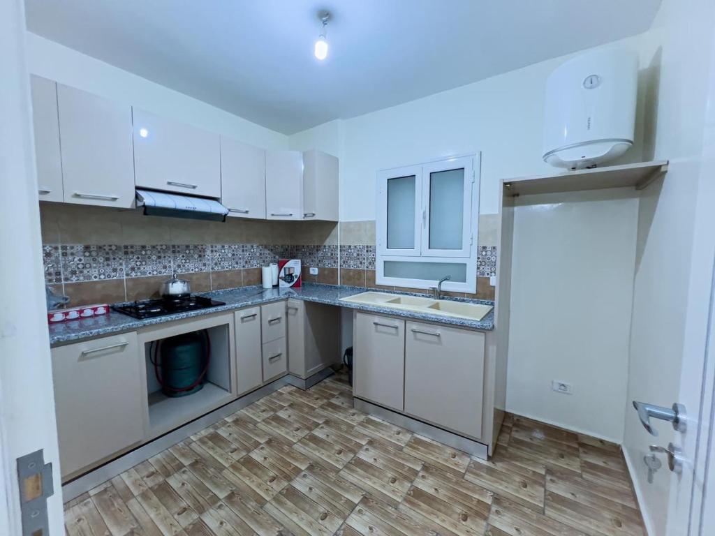 杰尔吉斯Residance saji的厨房铺有木地板,配有白色橱柜。
