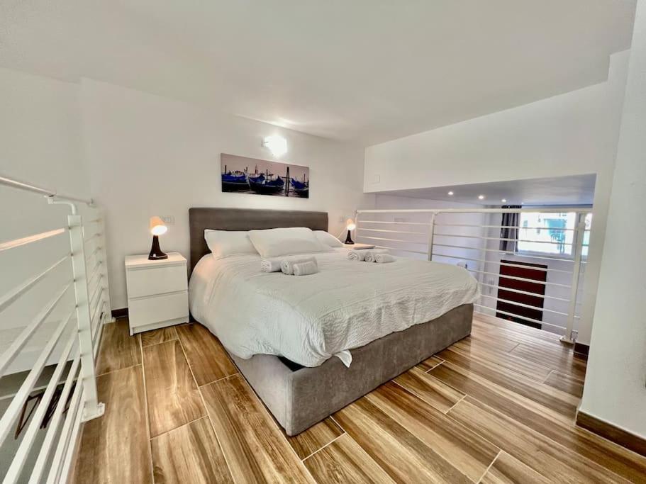 都灵Pregevole loft con soppalco的白色卧室设有一张大床和木地板