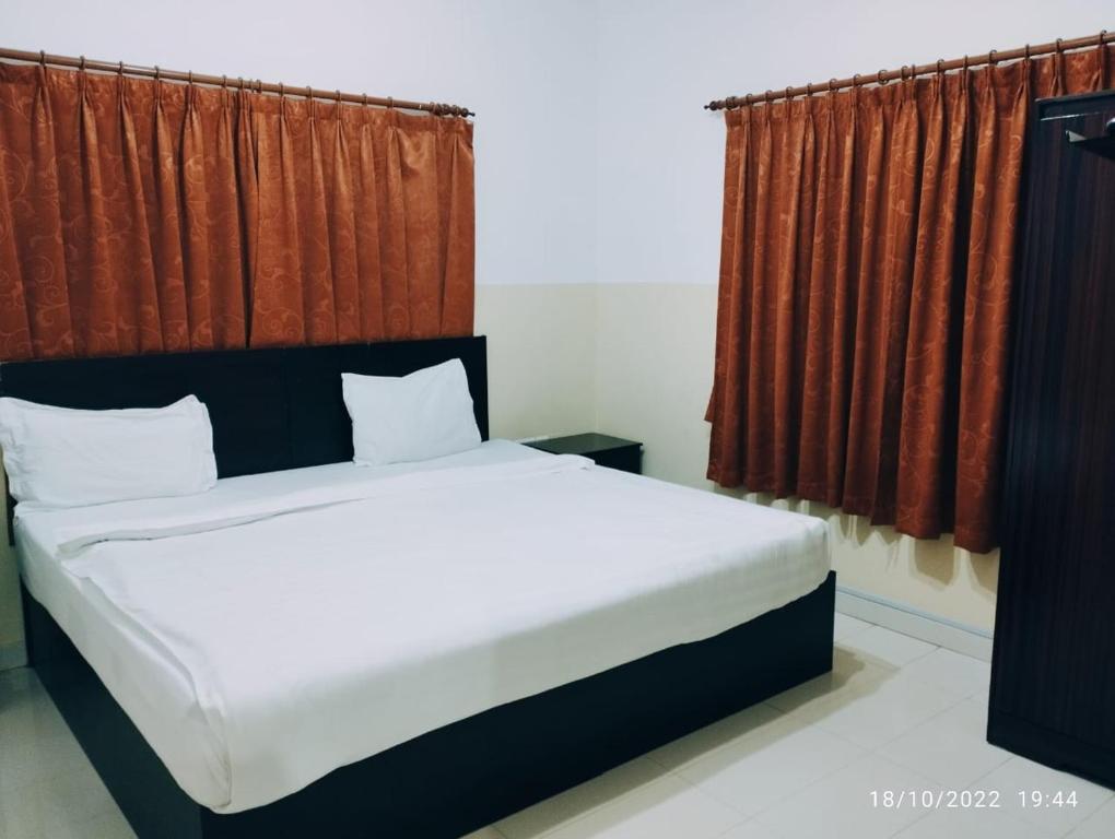 苏尔Al Basateen Hotel Apartment的一间卧室配有一张带红色窗帘的大床