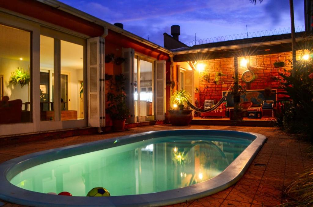 佩洛塔斯Pelotas Bier Hostel的夜间在房子前面的游泳池