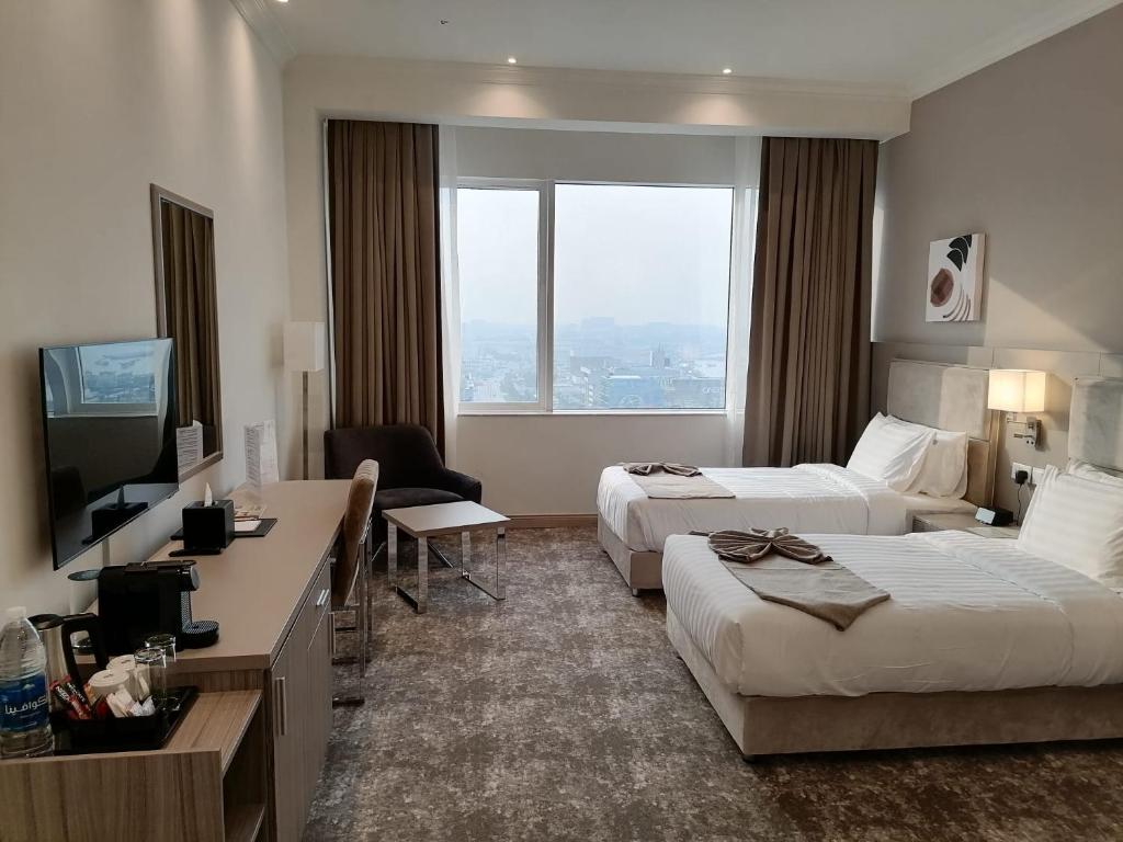 多哈Gloria Hotel & Suites Doha的酒店客房设有两张床和电视。