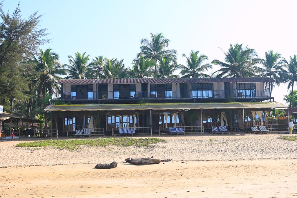 阿贡达Madhu Huts Agonda的沙滩上一座大建筑,沙滩上穿鞋