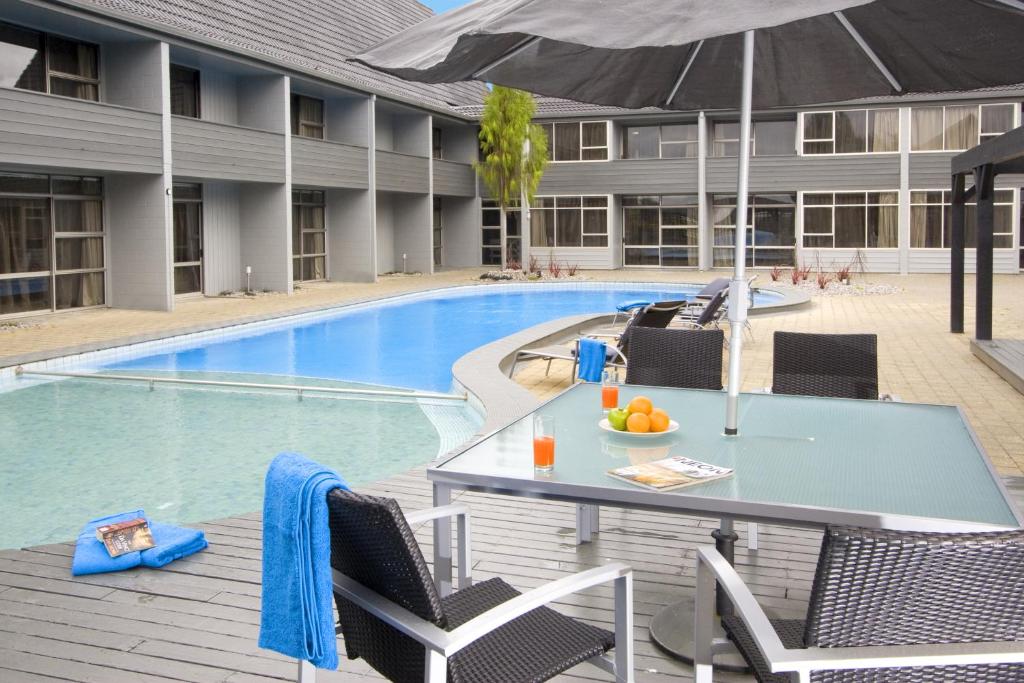 罗托鲁瓦罗托鲁瓦阿波罗大酒店的游泳池旁带遮阳伞的桌子
