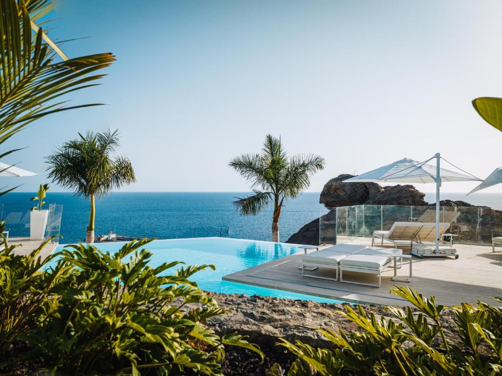波多黎各Grand Horizon Luxury Boutique Apartments的一个带椅子的游泳池,背景是大海