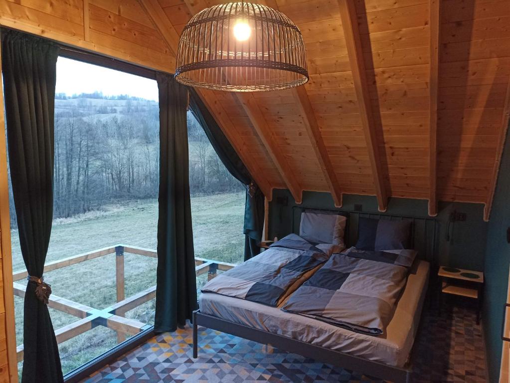 卡缅纳古拉Maraśka Holiday House的一间卧室设有一张床和一个大窗户