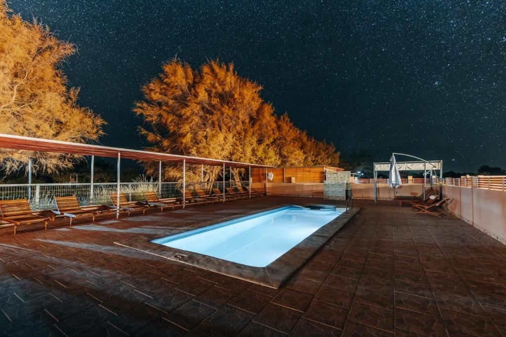 圣佩德罗·德·阿塔卡马Peumayen Atacama cabaña&Hostal的游泳池在晚上在庭院里