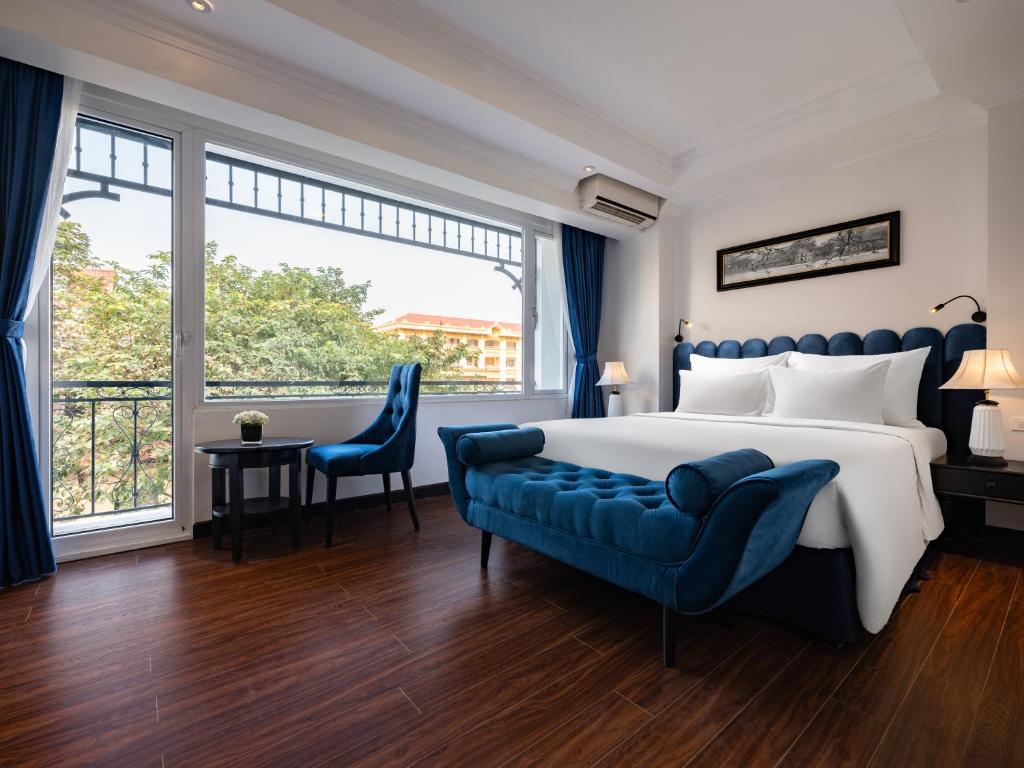 河内The Flower Boutique Hotel & Travel的一间卧室配有一张大床和一张蓝色的沙发