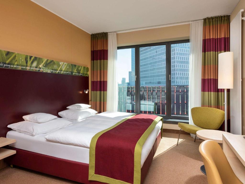 美因河畔法兰克福Mövenpick Hotel Frankfurt City Messe的酒店客房设有一张床和一个大窗户