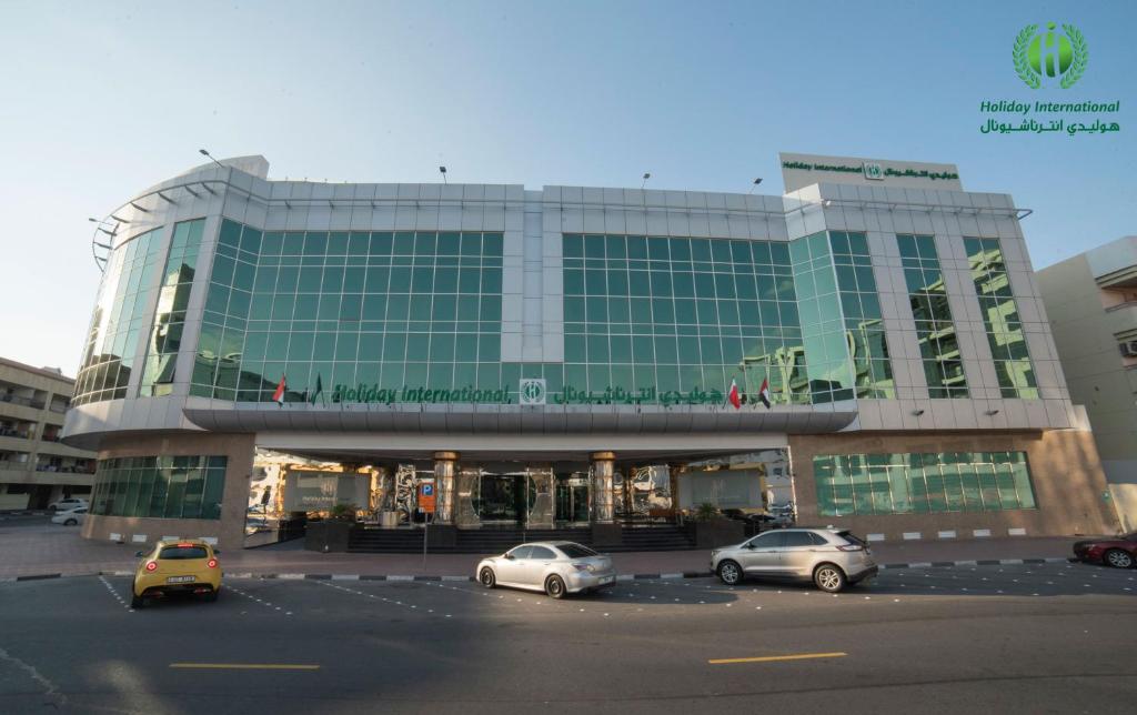 迪拜Holiday International Hotel Embassy District的停车场内停放汽车的大型建筑