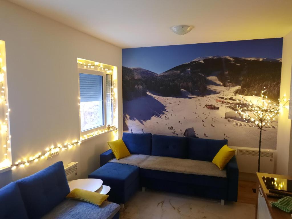 别拉什尼察Apartman White Wings Bjelasnica的客厅配有蓝色的沙发和山壁画
