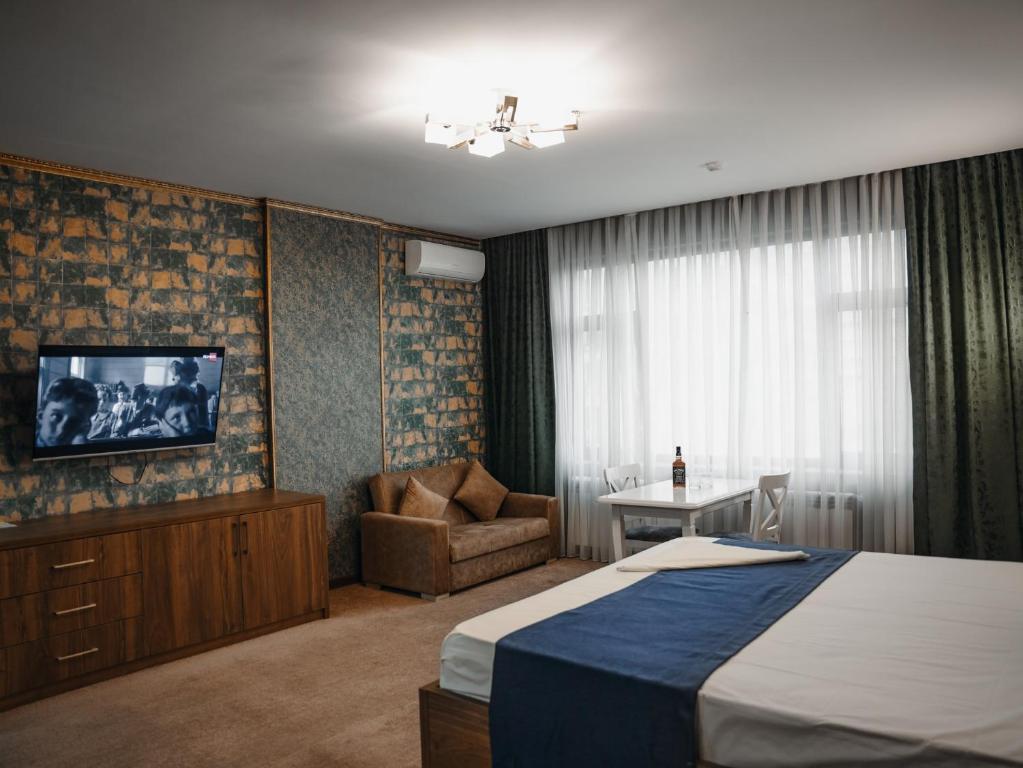 巴库Alison Hotel的酒店客房配有一张床、一把椅子和一台电视。