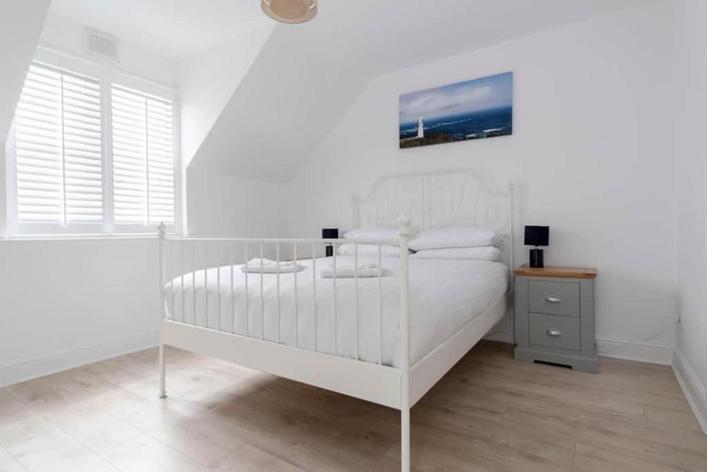 拉辛赫Modern newly refurbished house 10 minute walk from Lahinch的白色的卧室设有白色的床和窗户。