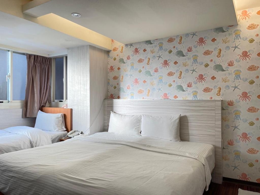 中坜中興商旅  的卧室内的两张床,墙上挂着鲜花