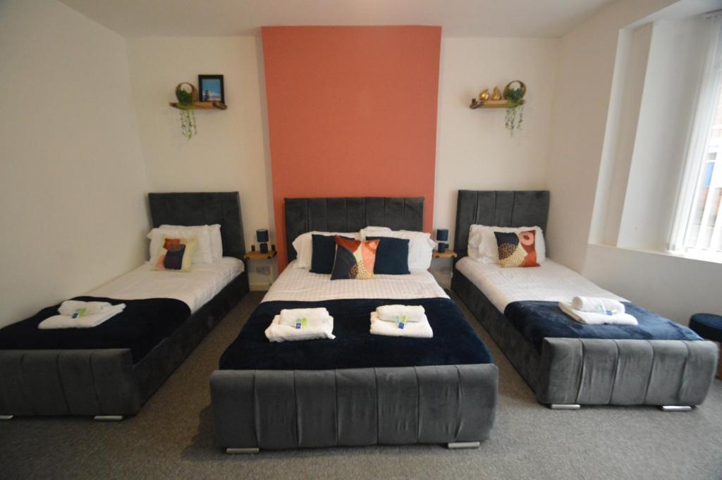 盖茨黑德Spacious and Homely 2 Bedroom Flat - SuiteLivin的一间卧室配有三张床和枕头。