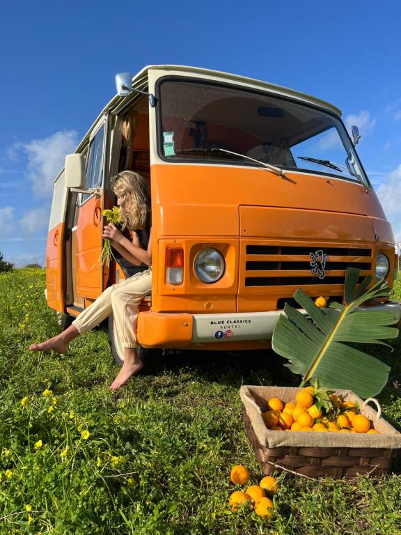 波尔蒂芒Rent a BlueClassics 's Campervan combi J9 en Algarve au Portugal的坐在橙色面包车前的女人