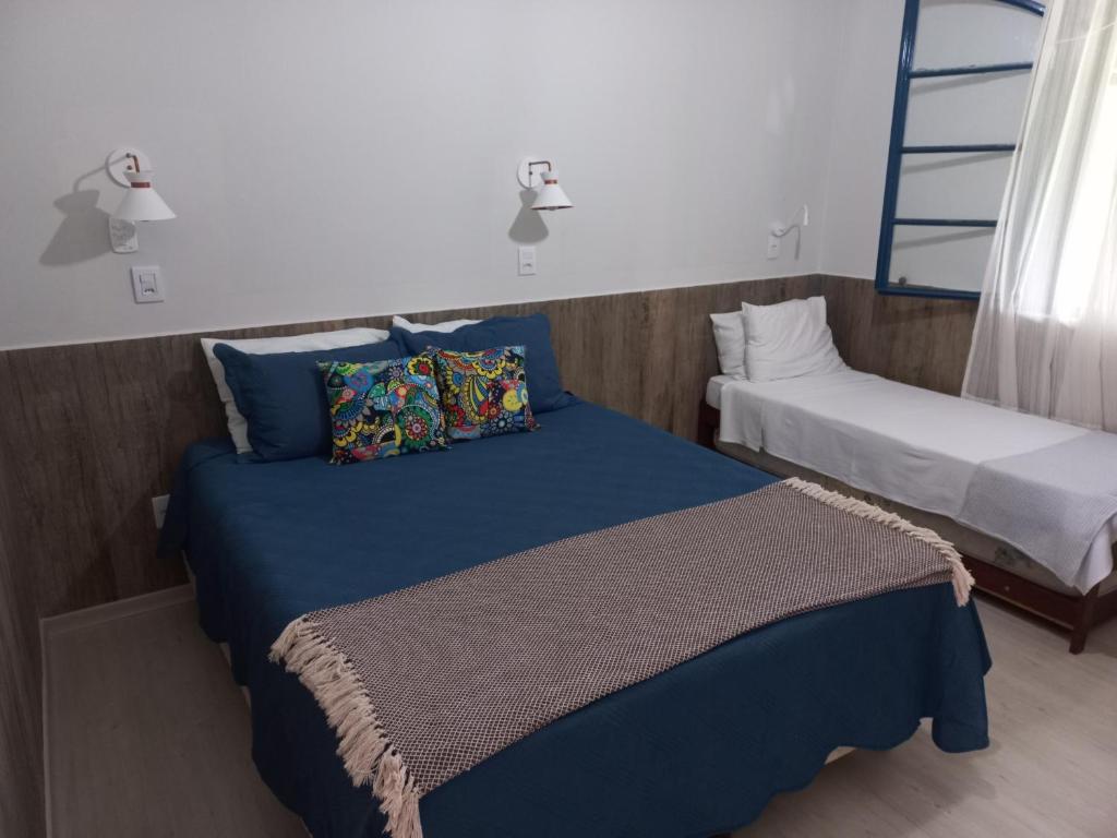 卡尚布Recanto Caminho das Águas的一间卧室配有两张蓝色床单
