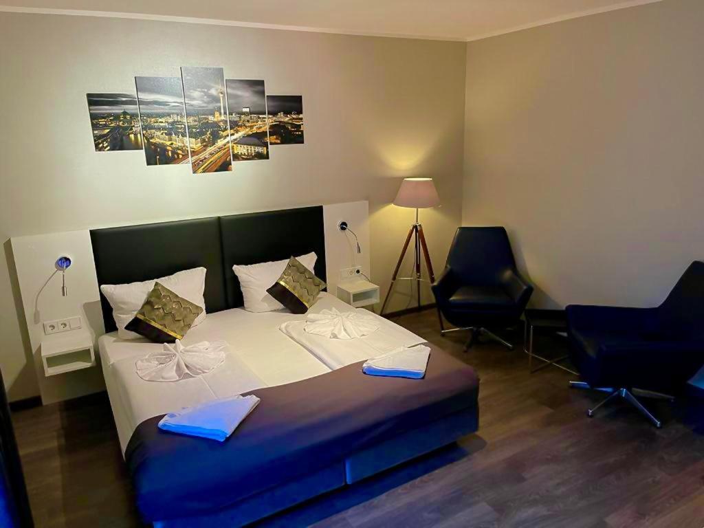 柏林阿尔法酒店的一间卧室配有一张大床和两把椅子