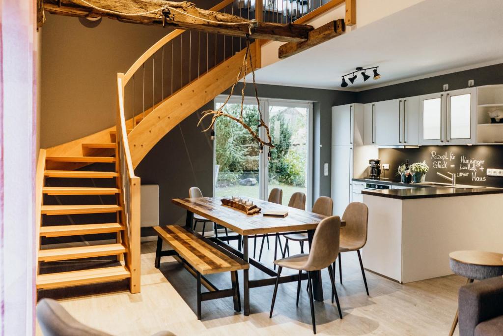 瓦尔斯罗德Ferienhaus Hünzingen的厨房以及带木桌和楼梯的用餐室。