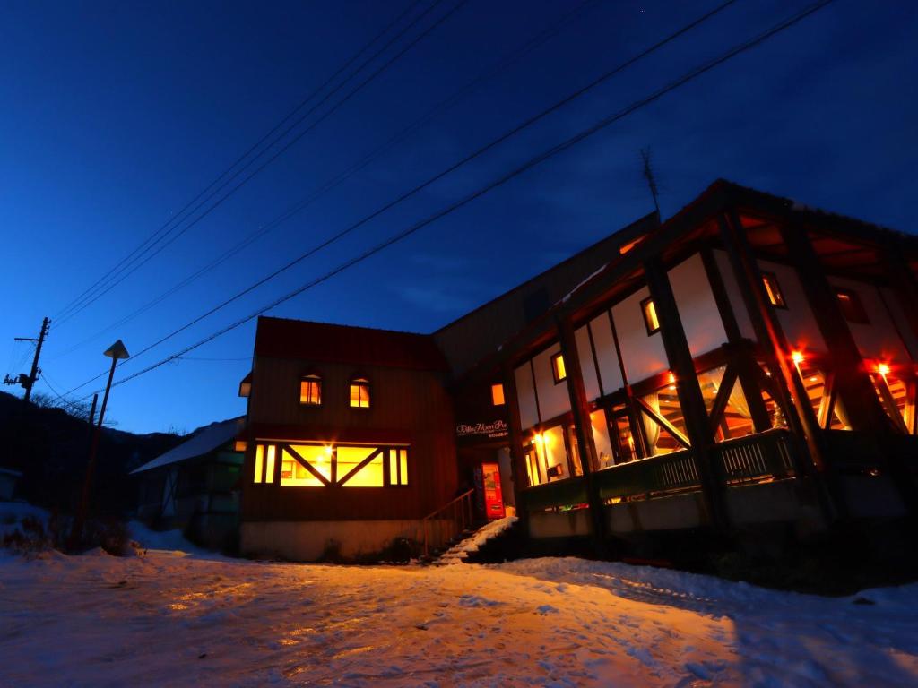 妙高蒙雷波斯别墅住宿加早餐旅馆的一座晚上在雪中亮着灯的建筑