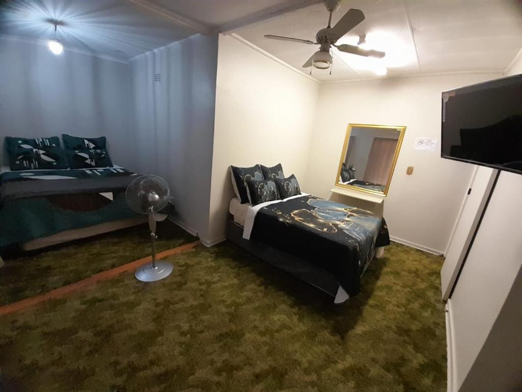 勒斯滕堡Pythons Guest Lodge的一间卧室配有一张床、镜子和风扇