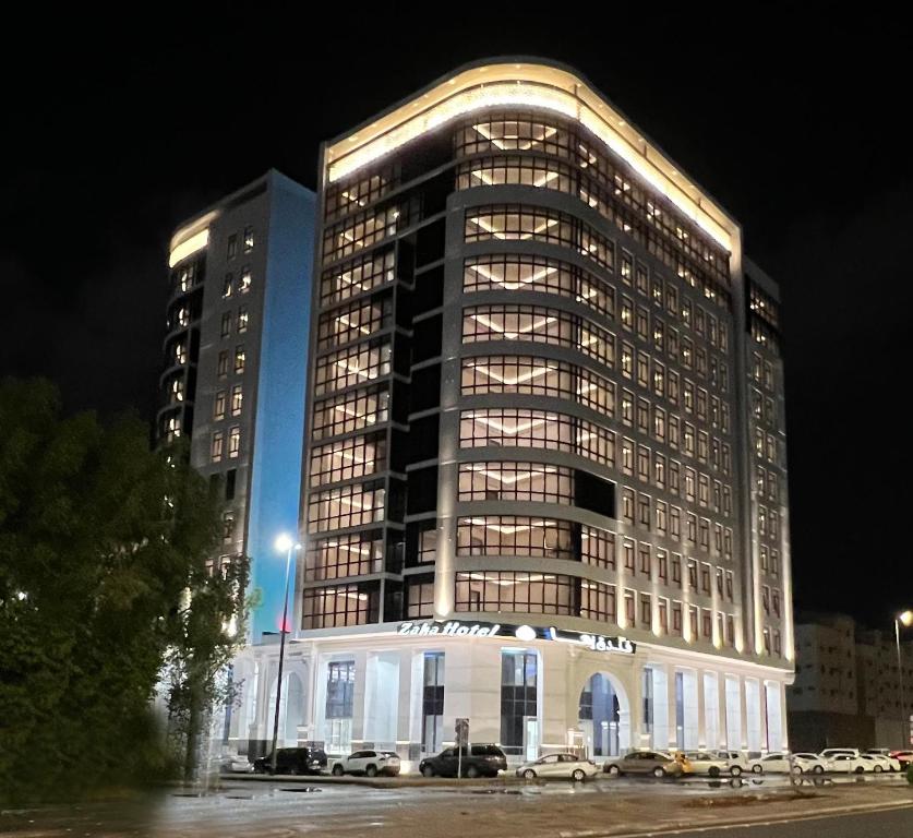 麦地那Zaha Taiba Hotel的一座大型建筑,在晚上停在前面